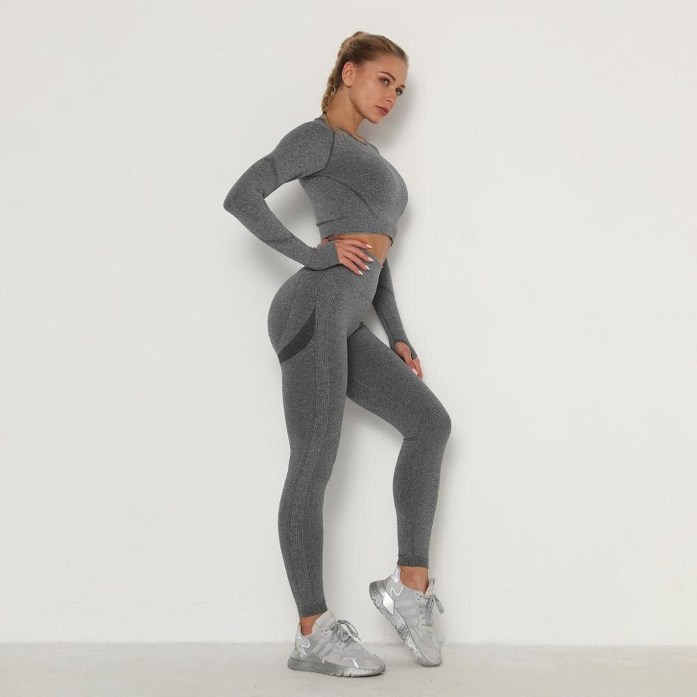 Frau in grauem nahtlosem Sport-Set, langärmeliges Oberteil, Leggings, Fitnessmode.