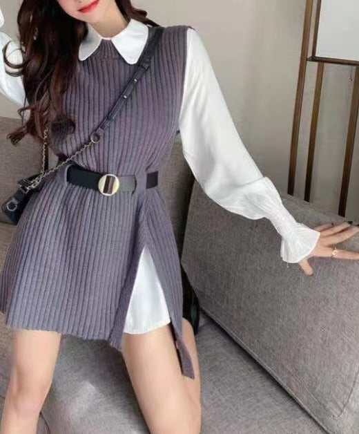 Frau in grauem Strickkleid mit Gürtel und weißer Bluse auf grauem Sofa.