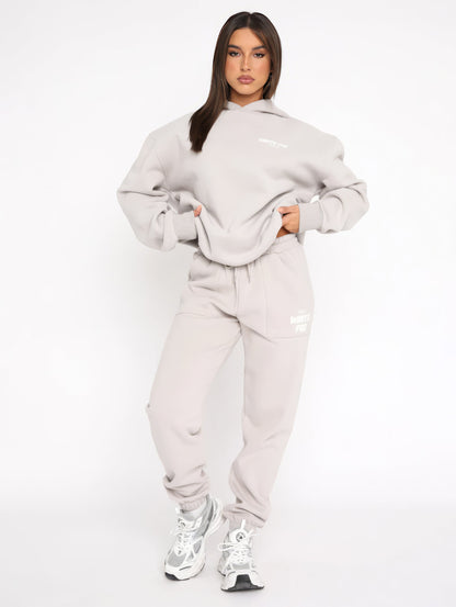 Frau in grauem Hoodie und Jogginghose, sportlich, lässig, Streetwear, Mode, Sneakers.