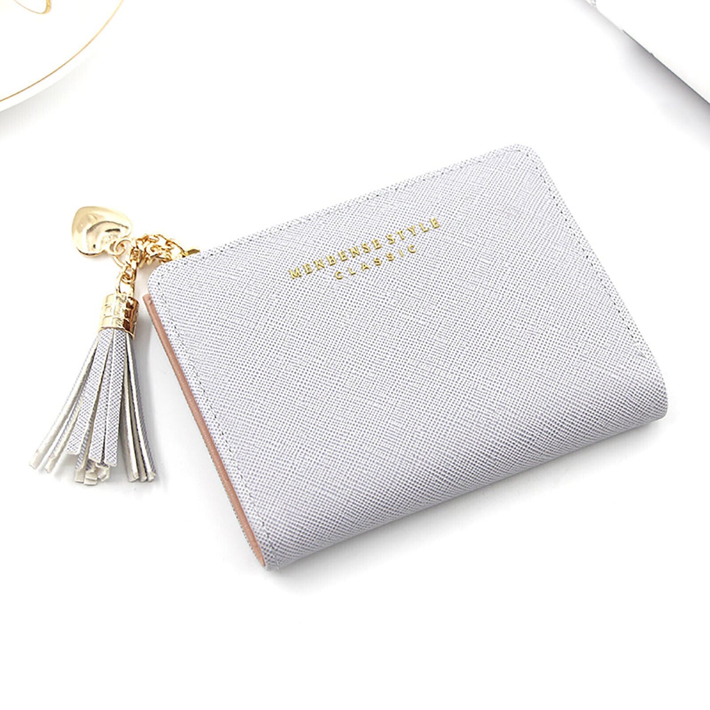 Graues Damenportemonnaie aus Leder mit Quaste und goldenen Akzenten, elegant und stilvoll.