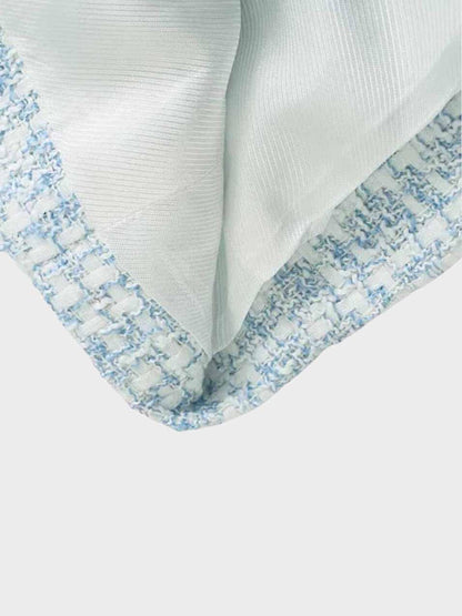 Nahaufnahme eines karierten Tweed-Blazers in Blau und Weiß, Stoffdetail, modisch, elegant.