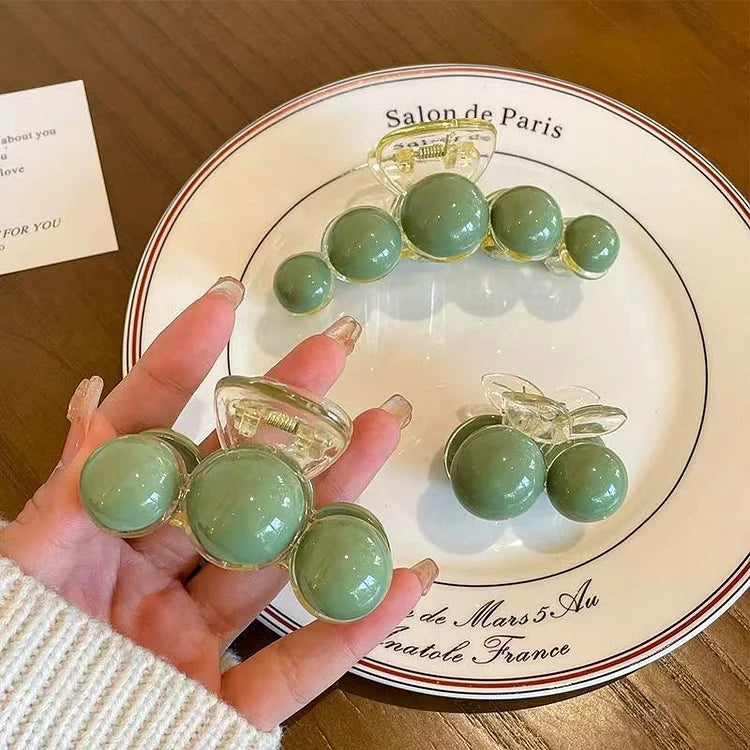 Grüne Haarspangen aus Kunststoff auf Teller, modisches Accessoire, stilvoller Haarschmuck.