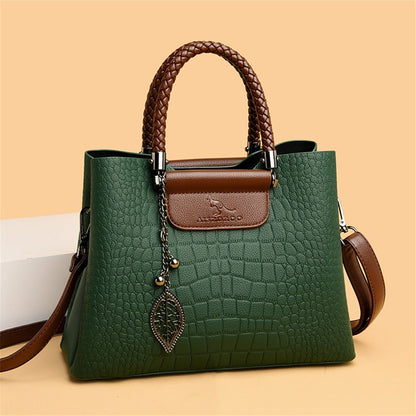 Grüne Damenhandtasche aus Leder mit braunen Griffen und Blattanhänger, elegant und modisch.