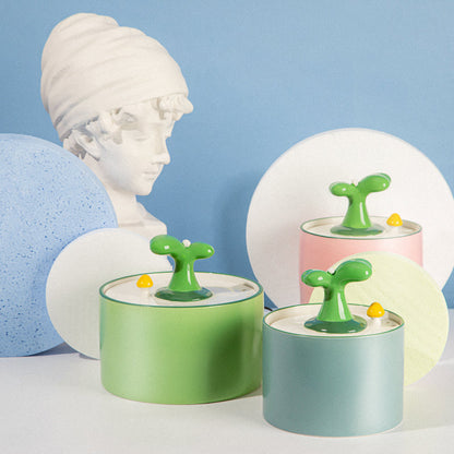 Deko-Objekte mit grünen Knöpfen, pastellfarbenen Dosen, Büste im Hintergrund, modernes Design.