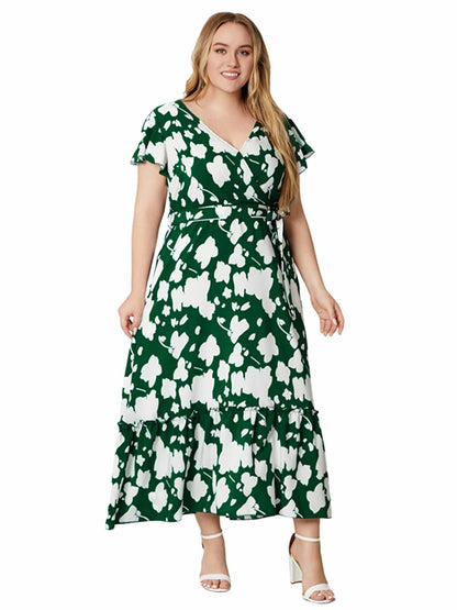 Frau im grünen Maxikleid mit weißem Blumenmuster, V-Ausschnitt, kurze Ärmel, Sommermode.