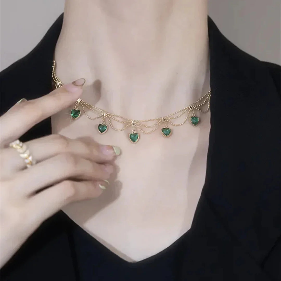 Goldene Halskette mit grünen Herzanhängern, eleganter Schmuck für Damen, modisches Accessoire.