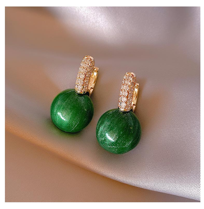 Grüne Ohrringe mit goldenen Details und Strasssteinen auf Seide, eleganter Schmuck.