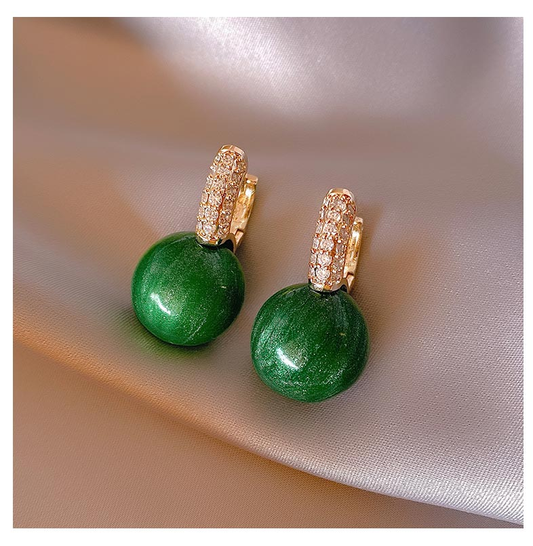 Grüne Ohrringe mit goldenen Details und Strasssteinen auf Seide, eleganter Schmuck.