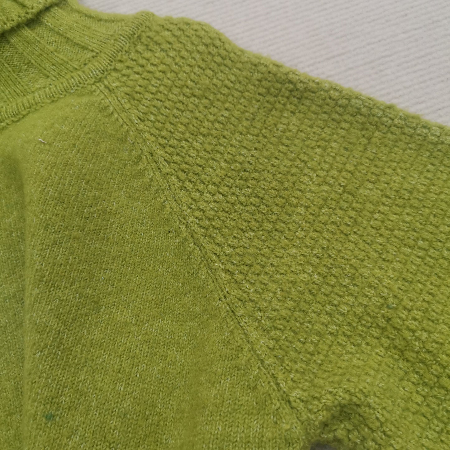 Grüner Strickpullover aus Wolle, Nahaufnahme, Texturdetail, modisch, warm, bequem.