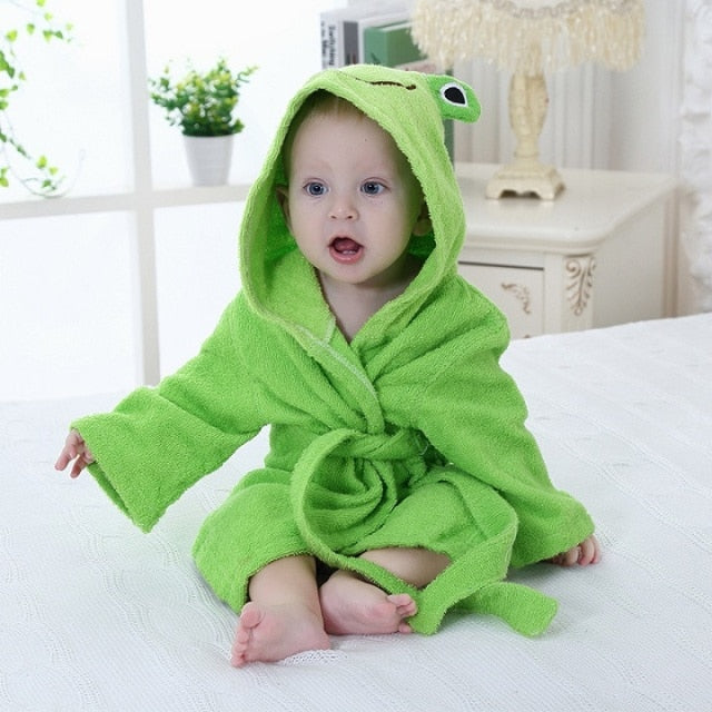 Baby in grünem Frosch-Bademantel auf Bett, Kinderbademantel, weiches Frottee, Kapuze.