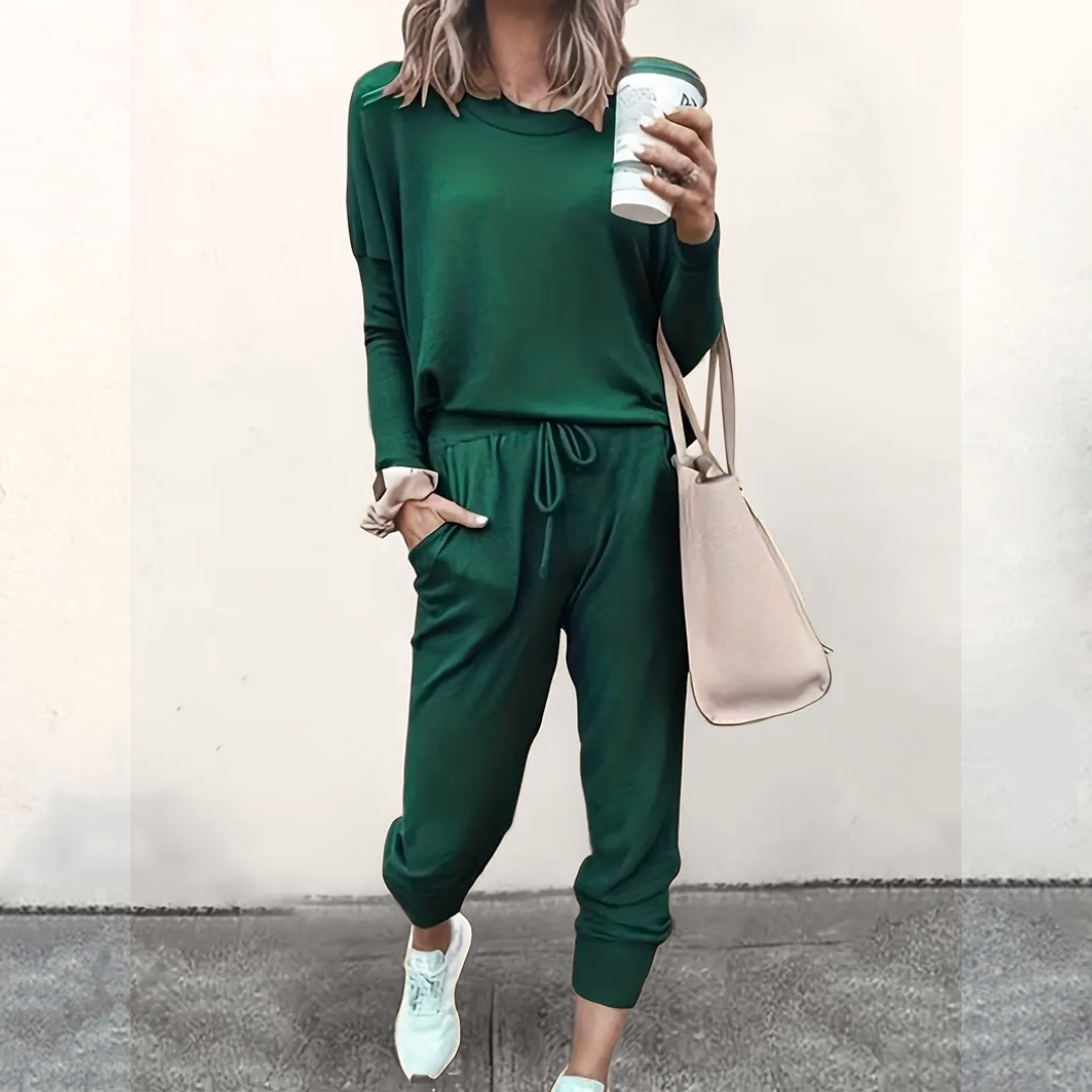 Frau in grünem Jogginganzug mit Kaffeebecher und beiger Tasche, lässige Mode.