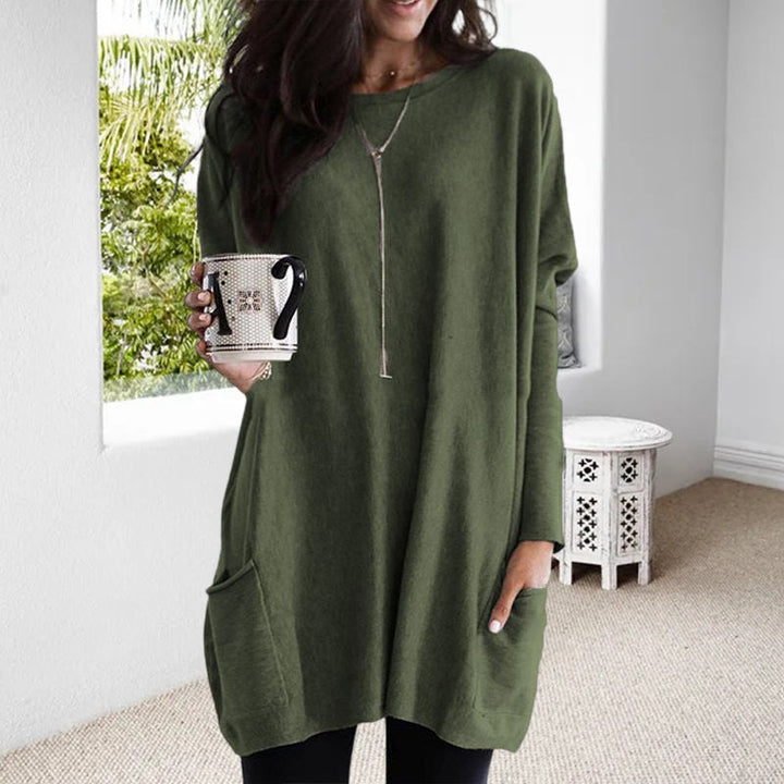 Frau in grünem Oversize-Pullover mit Tasse, lässige Mode, Wohnzimmer, Herbstkleidung.