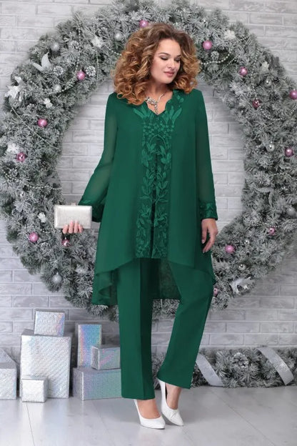 Frau in eleganter, grüner Festtagsmode vor weihnachtlichem Kranz, hält silberne Clutch.