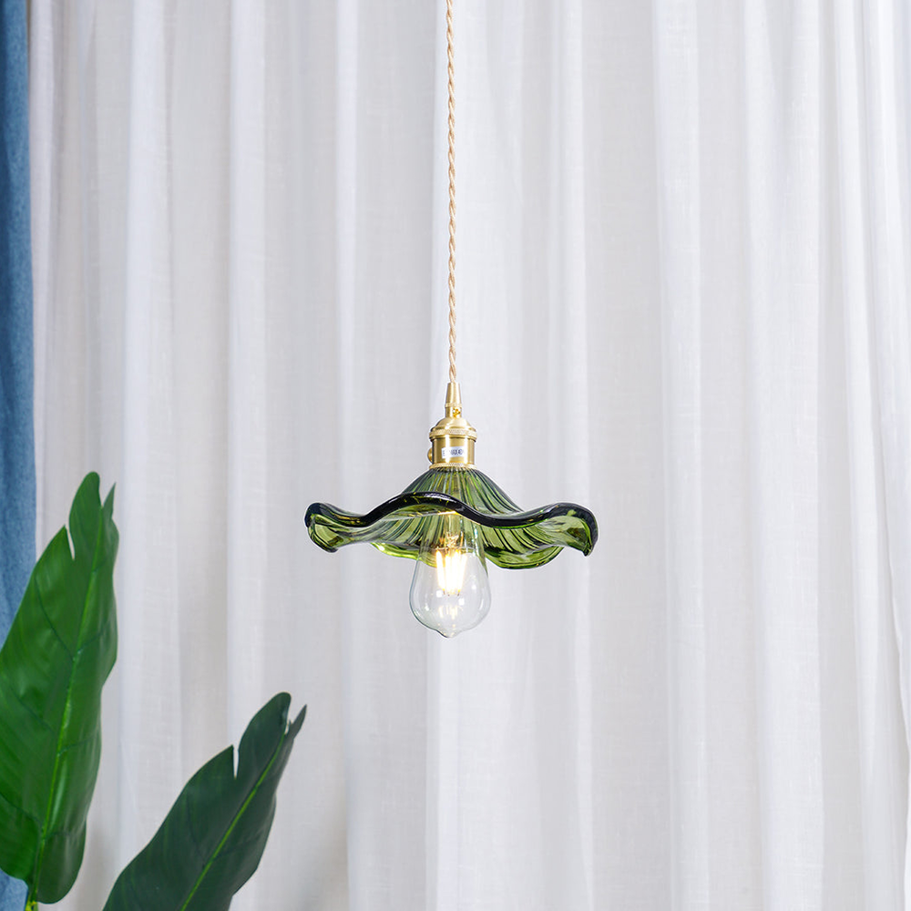 Grüne Glas-Pendelleuchte mit goldener Fassung, Vintage-Design, vor weißem Vorhang.