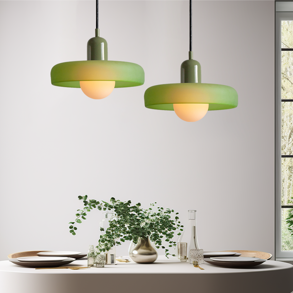 Grüne Hängelampen über Esstisch mit Geschirr und Vase, modernes Innendesign, Beleuchtung.