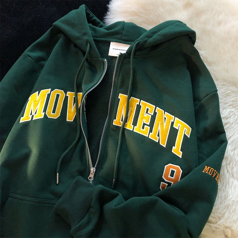 Dunkelgrüner Kapuzenpullover mit gelbem "MOVEMENT" Schriftzug, Reißverschluss, Baumwolle.