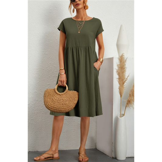 Frau in olivgrünem Baumwoll-Leinen-Kleid, A-Linie, kurze Ärmel, mit Strohtasche, Sommermode.