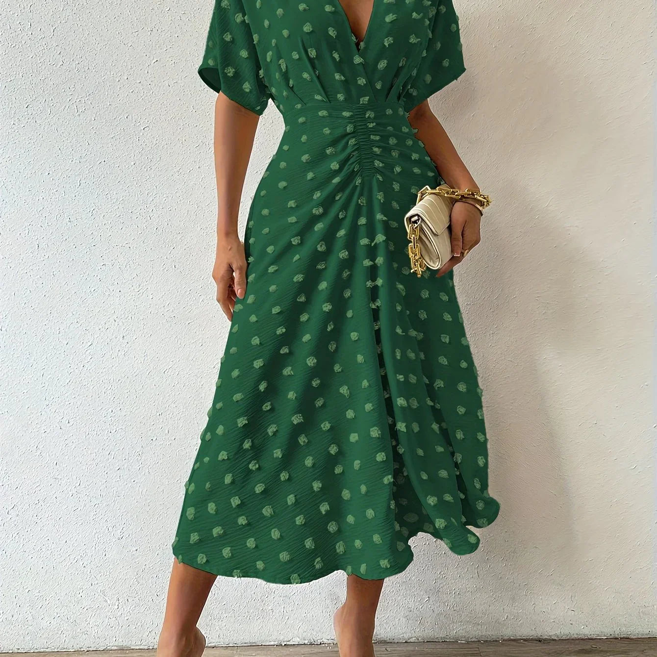 Grünes Damenkleid mit V-Ausschnitt, gepunktet, knielang, elegant, Sommermode.