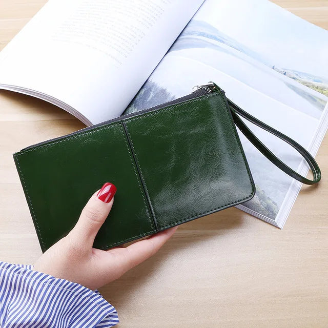 Grüne Lederhandtasche mit Reißverschluss, Damenmode, elegantes Accessoire, auf Holztisch.