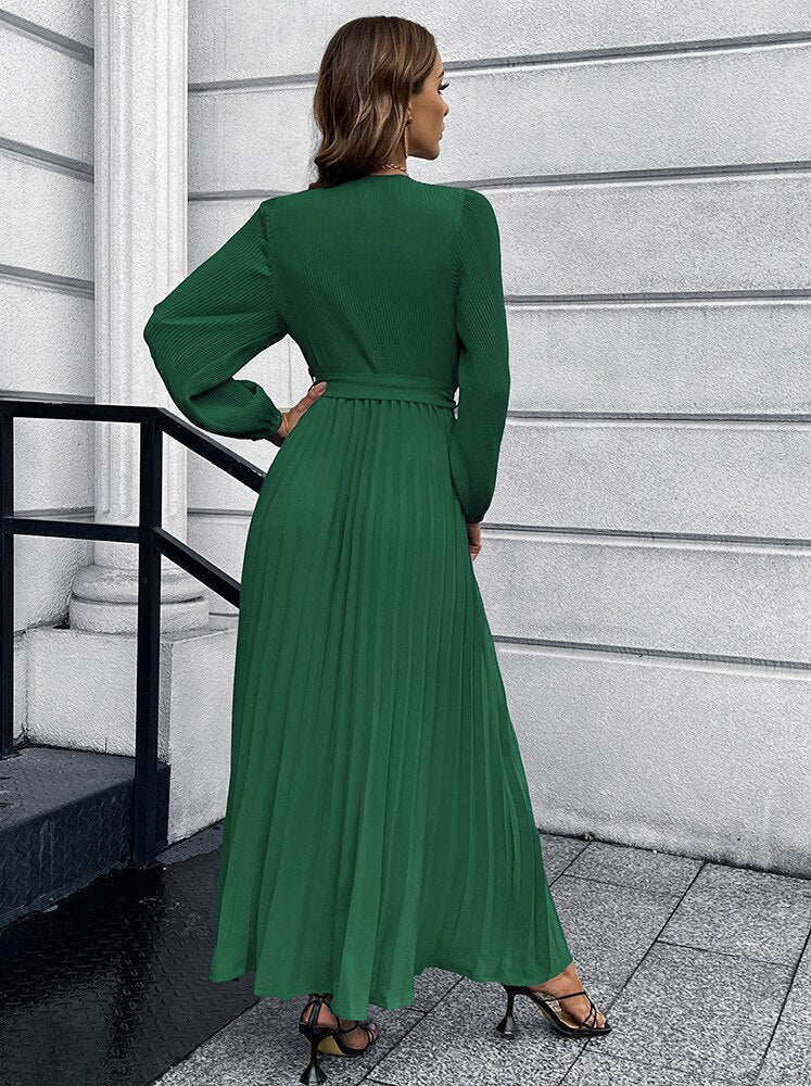 Frau in langem, grünem, plissiertem Kleid, elegantes Design, modische Abendgarderobe.