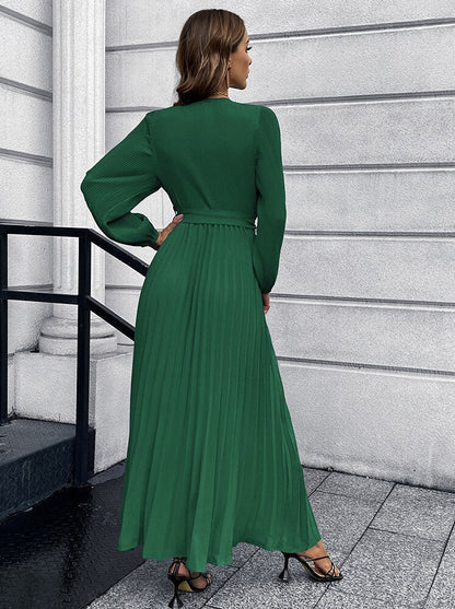Frau in langem, grünem, plissiertem Kleid, elegantes Design, modische Abendgarderobe.