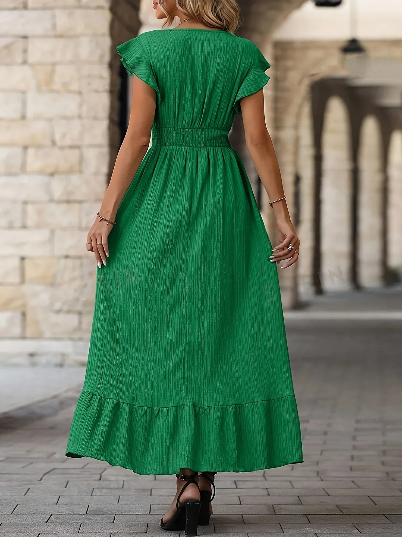 Frau in grünem Maxikleid aus Baumwolle, Rückansicht, elegantes Sommeroutfit, Stadtstraße.