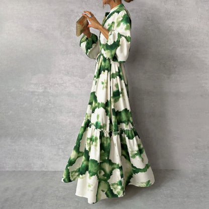 Frau im langen, grünen Batik-Kleid aus Baumwolle, seitlich, vor grauem Hintergrund.