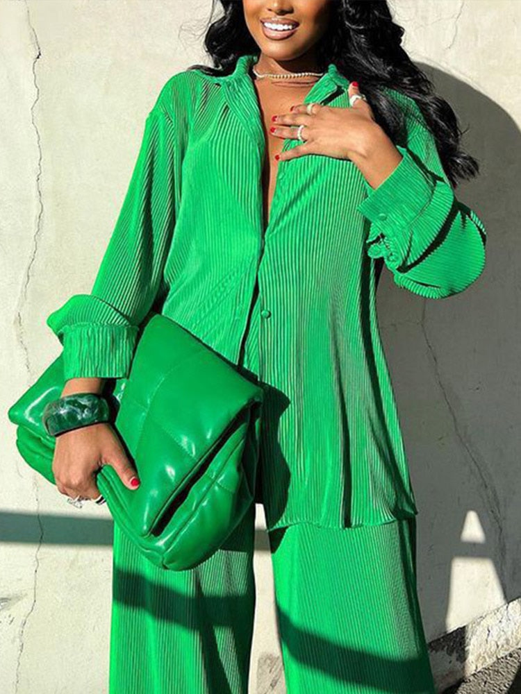 Frau in grünem Plissee-Outfit mit passender Tasche, modisch, elegant, Streetwear.