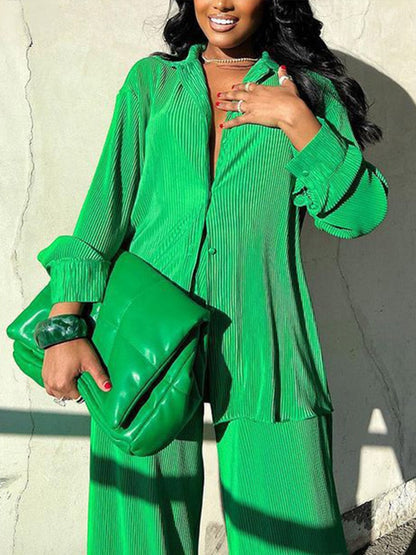 Frau in grünem Plissee-Outfit mit passender Tasche, modisch, elegant, Streetwear.