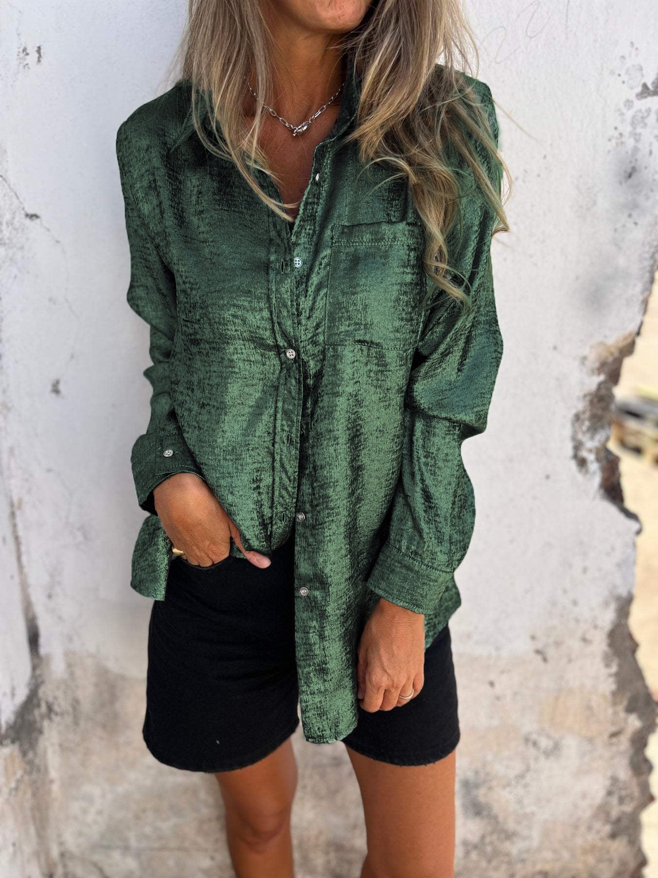 Grüne Seidenbluse Damen, langärmelig, elegant, mit Knöpfen, lässig, modisch, vor weißer Wand.