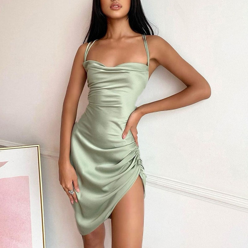 Frau in grünem Satin-Minikleid mit Spaghettiträgern, elegantes Abendmode-Outfit.
