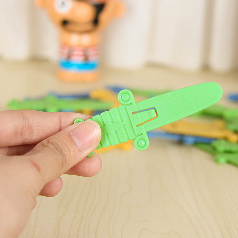 Grünes Plastikspielzeug-Schwert, handgehalten, auf Holztisch, Kinderspielzeug.
