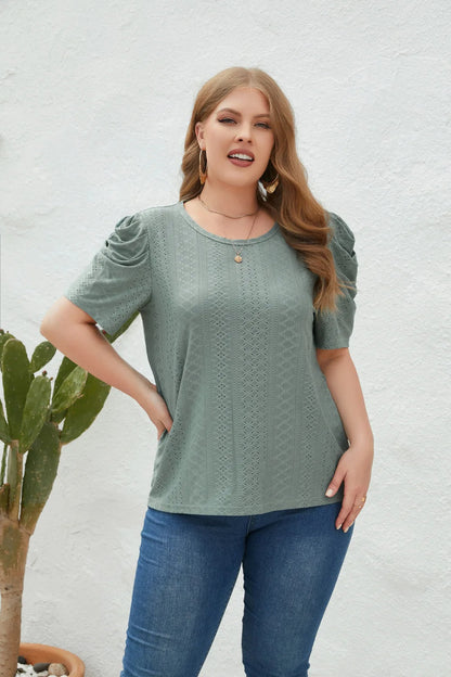 Frau in grünem Spitzen-T-Shirt und blauer Jeans vor weißer Wand, Mode, Freizeitkleidung.