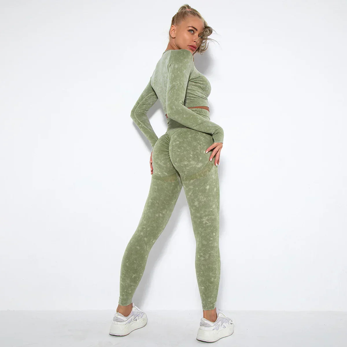 Frau in grünem Sportanzug, nahtlose Leggings, Fitnessmode, Rückansicht, weiße Turnschuhe.