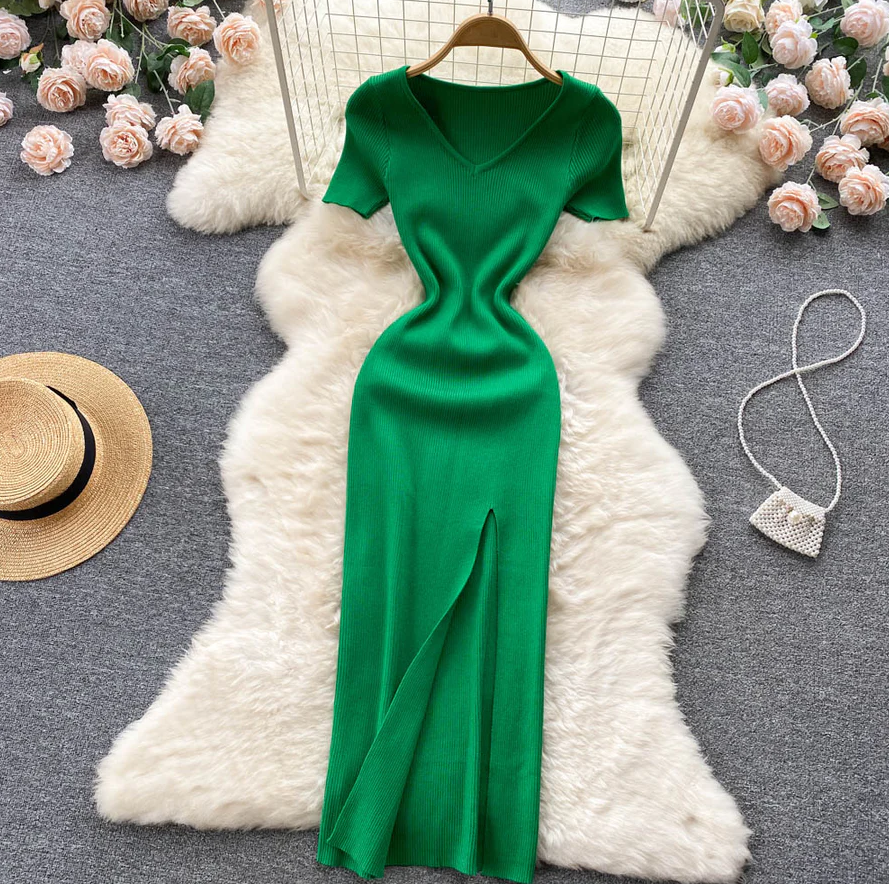 Grünes Strickkleid mit V-Ausschnitt, langem Schlitz, auf weißem Fell, umgeben von Rosen.