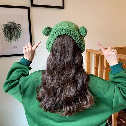 Frau mit grünem Strickmütze und grünem Pullover zeigt auf Wandkunst, Rückansicht.