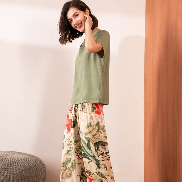 Frau in grünem T-Shirt und geblümter Hose, lächelnd, modisch, lässig, Sommerkleidung.