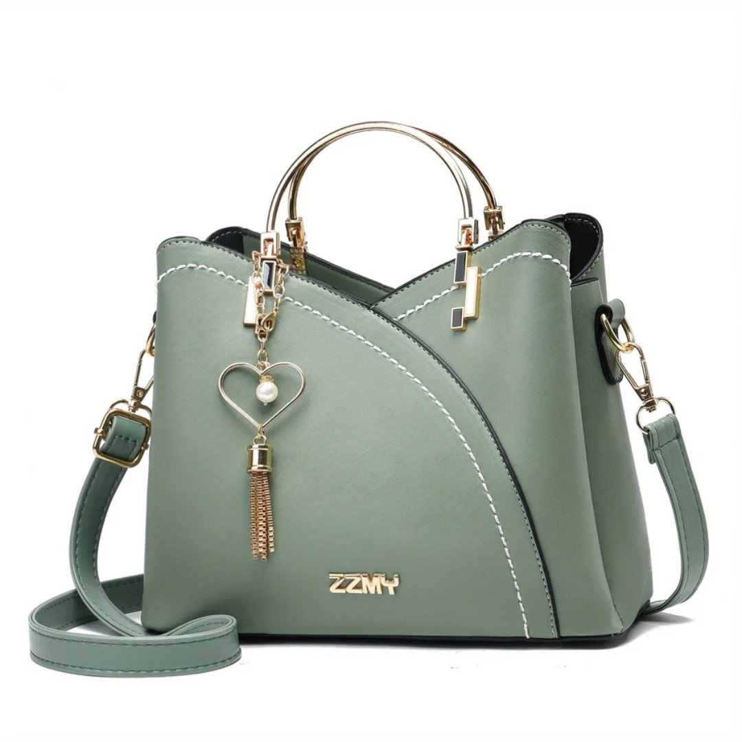Grüne Damenhandtasche mit goldenen Griffen und Herzanhänger, modisch und elegant.