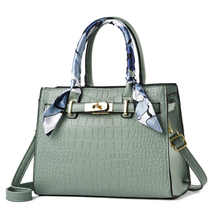 Grüne Damenhandtasche aus Leder mit Krokodilprägung und Seidenschal, modisch und elegant.