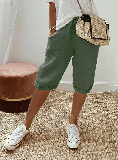 Damen Leinenhose grün, knielang, lässig, Sommermode, mit weißem T-Shirt und Sneakers.