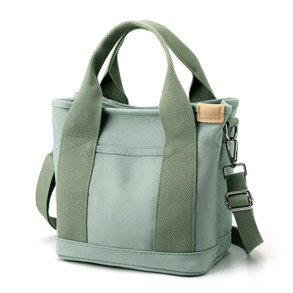 Grüne Canvas-Tasche mit Schulterriemen, robustes Design, ideal für Alltag und Reisen.