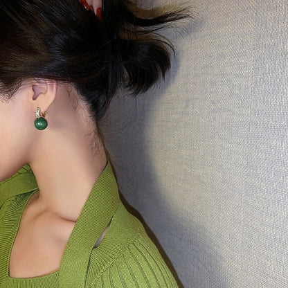 Frau mit grünen Ohrringen und grünem Pullover, eleganter Schmuck, Modeaccessoire.