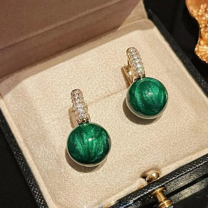 Grüne Perlenohrringe in Schmuckschatulle, luxuriöse Party-Accessoires, goldene Details.
