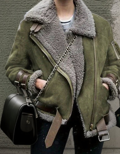 Grüne Lammfelljacke mit Reißverschluss, braunen Lederriemen und schwarzer Umhängetasche.