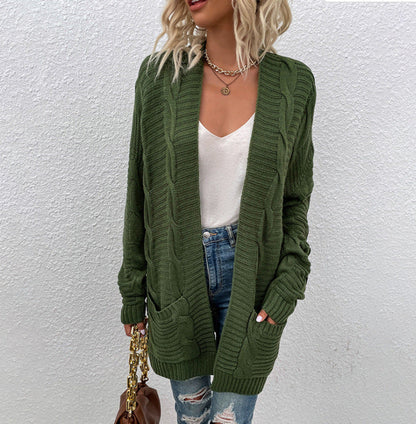 Frau in grünem Strickcardigan, weißem Top, Jeans; modischer Herbst-Look.