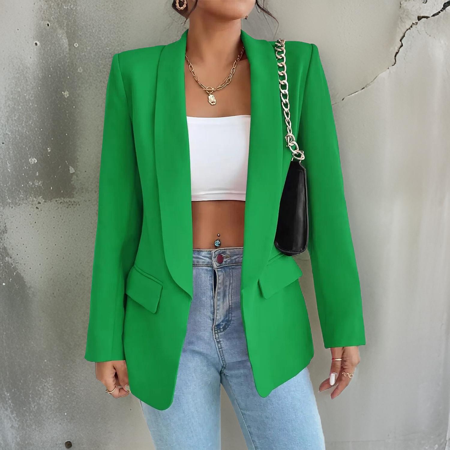 Frau in grünem Blazer, weißem Top und blauer Jeans, modisch, urbaner Stil.