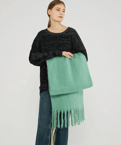 Frau mit schwarzem Pullover und grüner Wollschal mit Fransen, modisch, gemütlich, Herbstbekleidung.