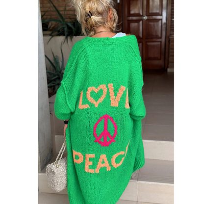 Frau mit grünem Strickponcho, Aufschrift "Love Peace", modisch, lässig, Rückansicht.