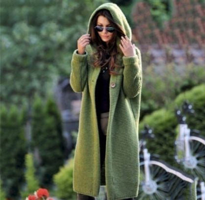 Frau in langem, grünem Strickmantel mit Kapuze, Sonnenbrille, draußen im Garten.