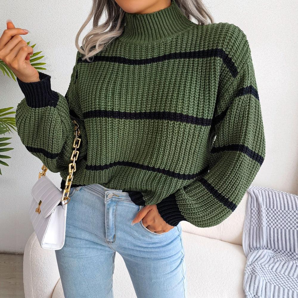 Frau in grünem Strickpullover mit schwarzen Streifen, hellblauer Jeans, weißer Handtasche.